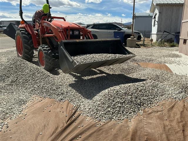 Tractor spreading gravel over landscape fabric