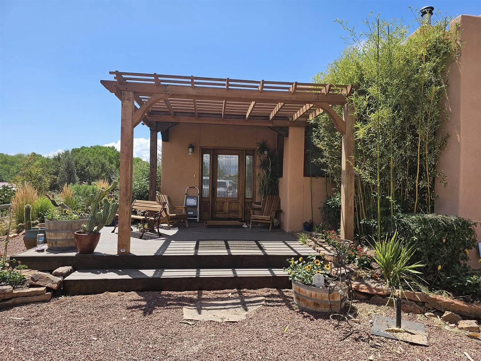 Home entrance with pergola, landscaped beds and wood deck